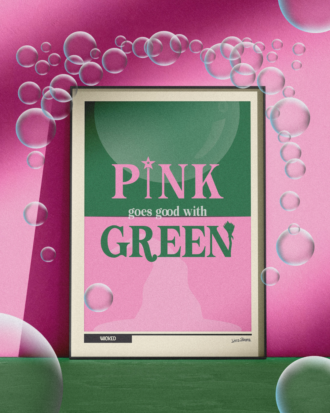 Pink Goes Good With Green Wicked poster in a black frame against a pink wall, surrounded by bubbles