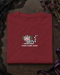 Axolotl Beetlejuice t-shirt in Burgundy, folded on a dark table with a lace veil and dried flowers