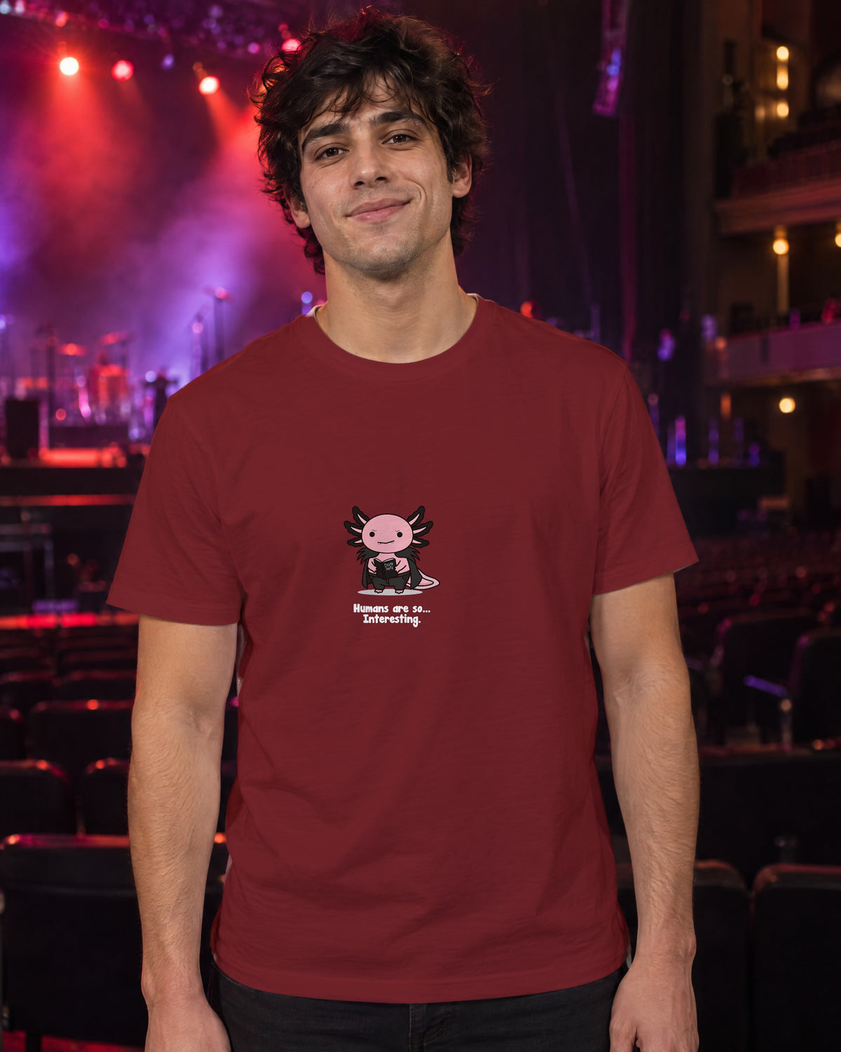Humans Are So Interesting t-shirt in Burgundy, worn in a theatre under red and violet stage light