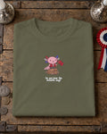 Do You Hear the Axolotls Sing t-shirt in Khaki, folded on a crate lid with silver candlesticks and a tricolour rosette