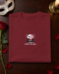 Axolotl of the Opera t-shirt in Burgundy, folded on a dressing table with a mask and a red rose